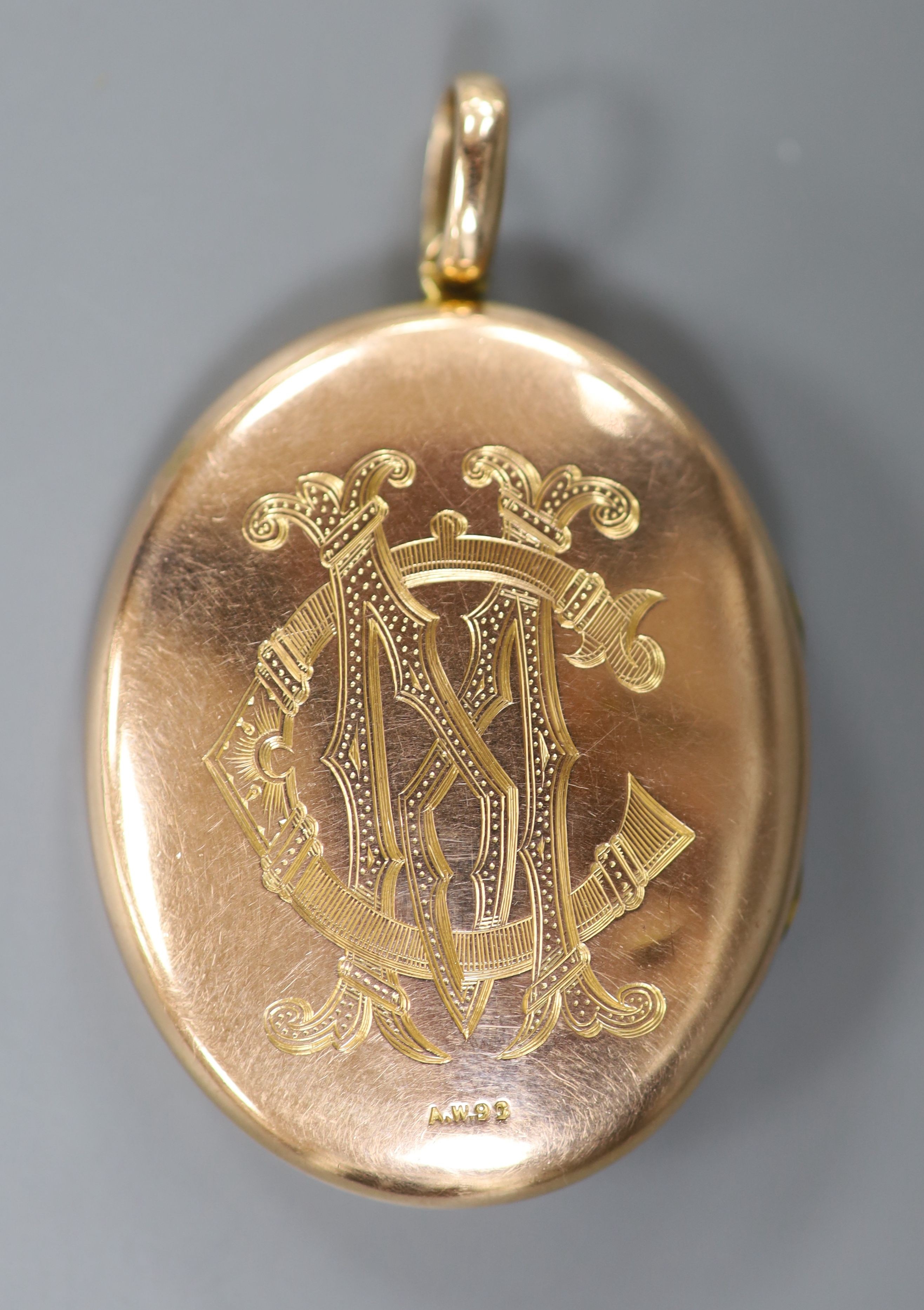 An early 20th century engraved yellow metal (stamped 9c) and split pearl set oval locket, 44mm, gross weight 13.5 grams, with engraved monogram.